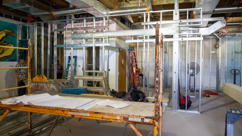 An indoor construction site, with men working in the background.