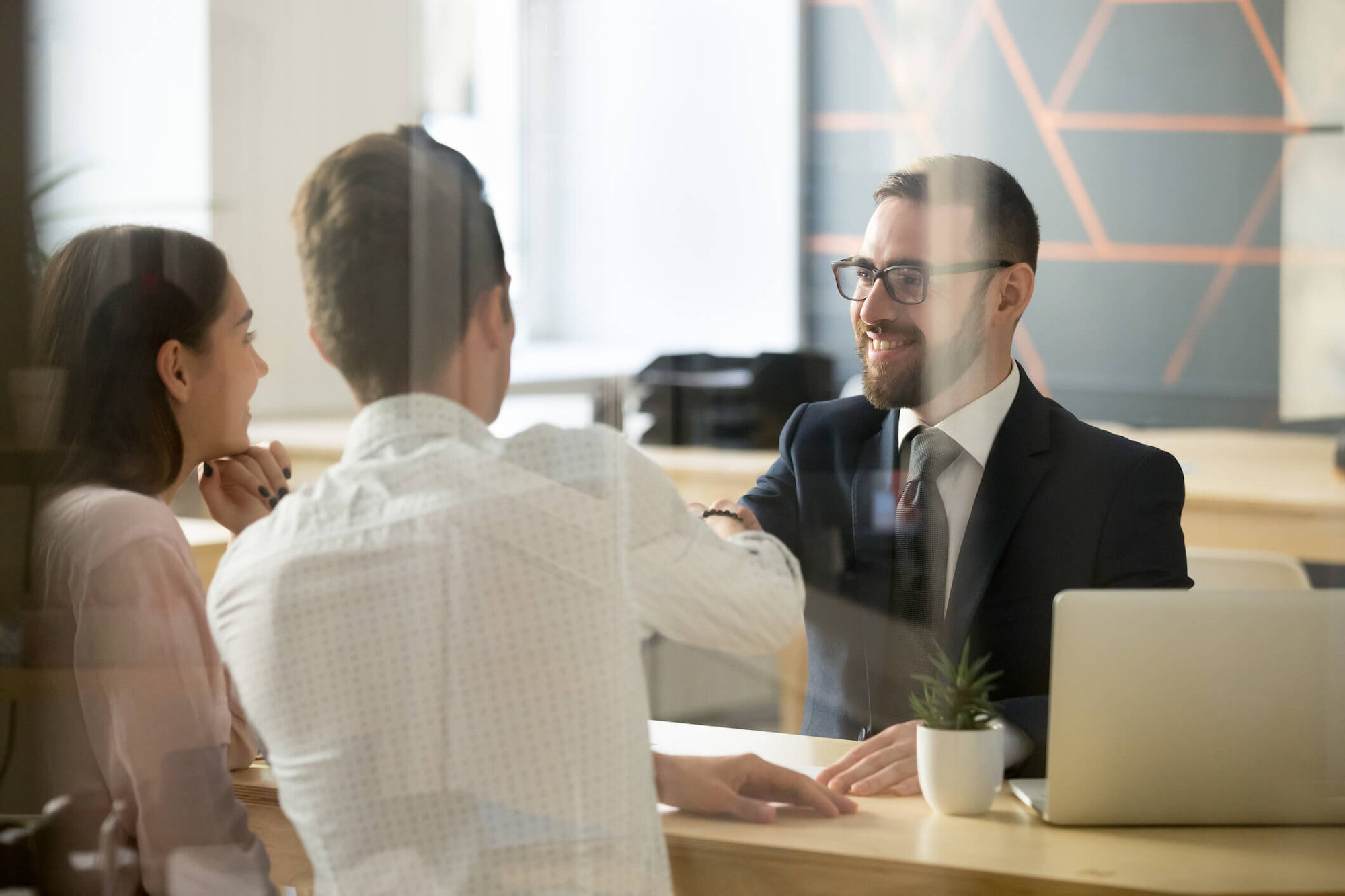 man in suit talking to couple across a desk