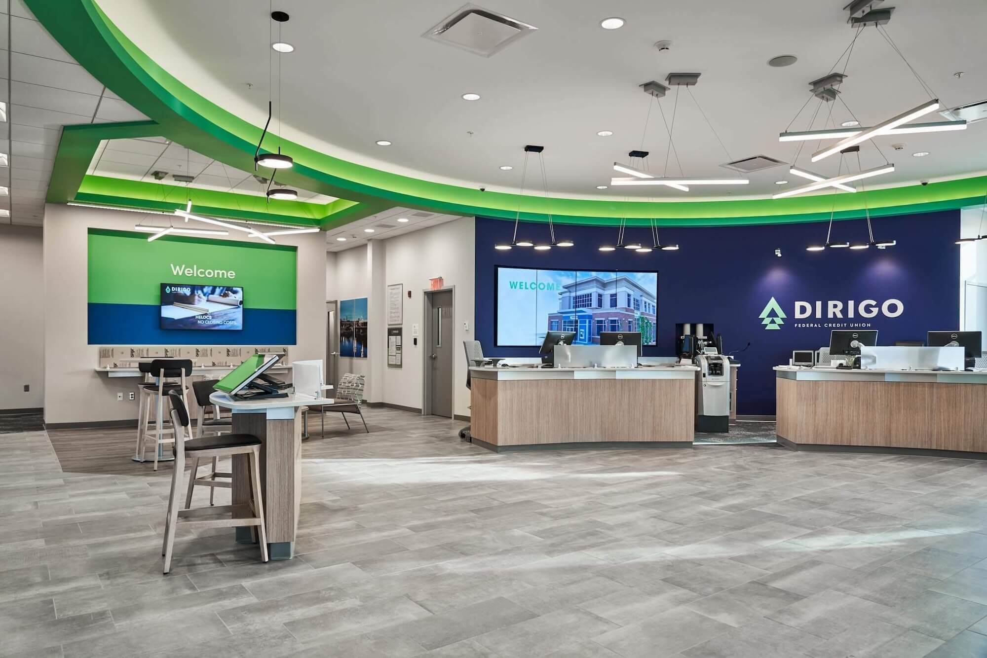 Credit union and bank interior design featuring an open floor plan, green and blue accent walls, sleek service counters, digital displays, and self-service kiosks.