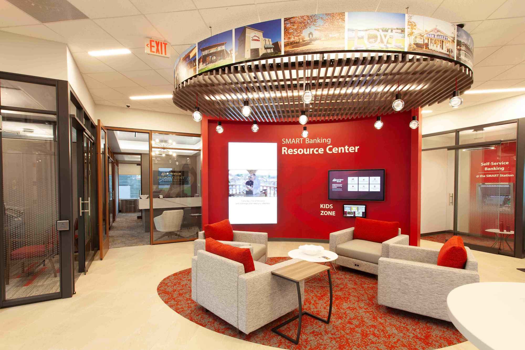 A contemporary office featuring vibrant red walls and a large display screen, creating a dynamic work environment.